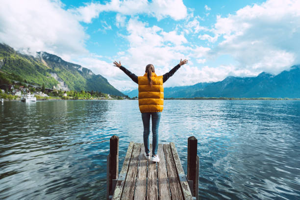 молодая женщина-путешественница с сеяниями стоит на деревянном мосту и наслаждается отличным видом на женевское озеро в швейцарии - geneva canton стоковые фото и изображения
