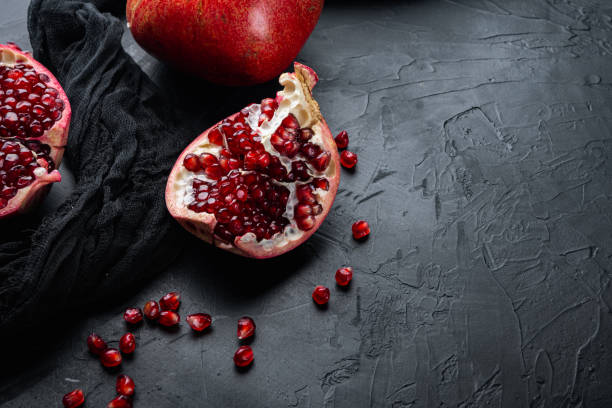 istock Ripe pomegranate with fresh juicy seeds, on black textured background with space for text 1326330621