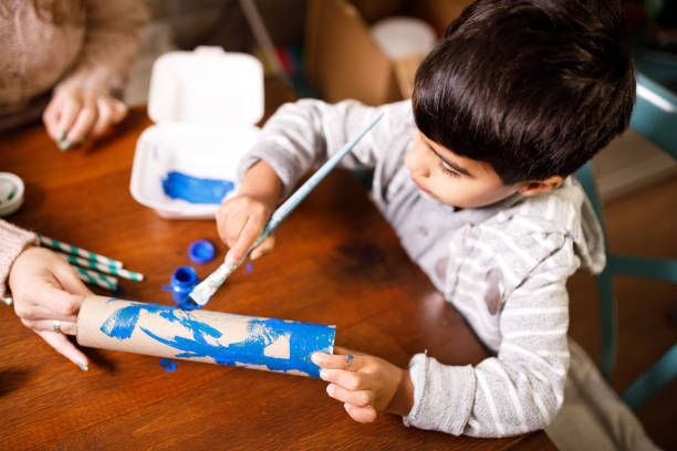Mother holding paper to her son paint