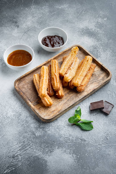 istock Typical Spanish snack  churros, fried-dough pastry served  usually with chocolate caramel hot sauce, on gray background 1326332884