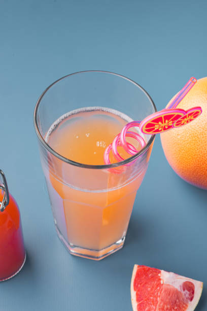 istock Pink grapefruit juice, on blue textured summer background 1326334286