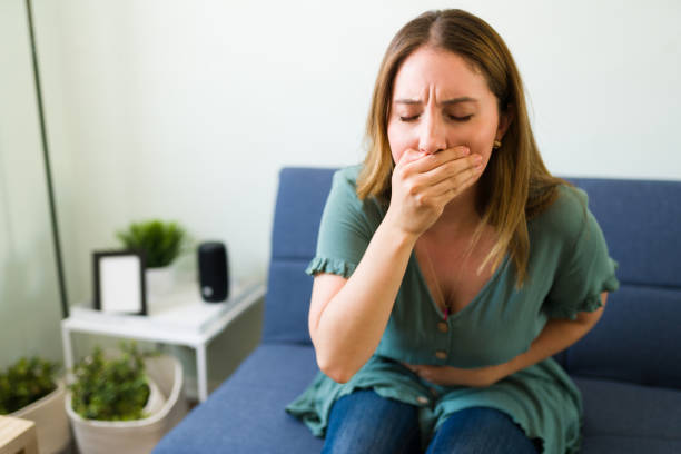 Sick woman trying not to throw up Attractive woman in her 20s about to vomit in the living room because of her stomach infection after eating bad food tetanospasmin stock pictures, royalty-free photos & images