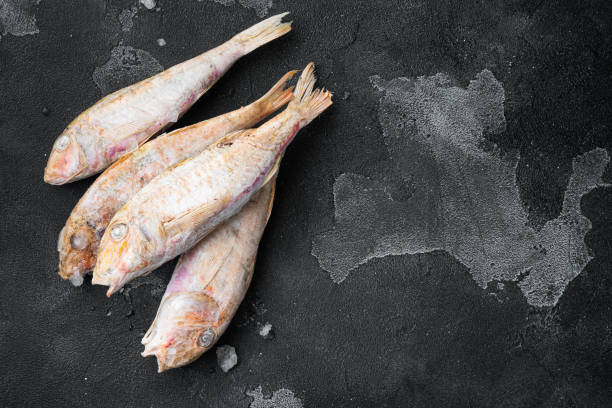 istock Frozen surmullet  fish, on black dark stone table background, top view flat lay , with copy space for text 1326337450