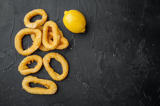 Squid rings or onion in breadcrumbs ingredients set, on black dark stone table background, top view flat lay, with copy space for text