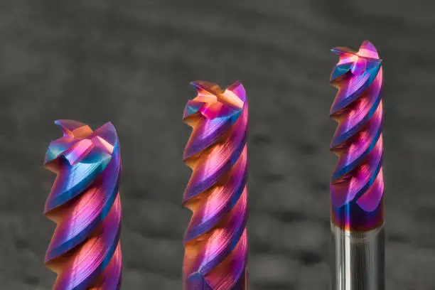Photo of Three steel end mills with beautiful colored nano coating on a gray background