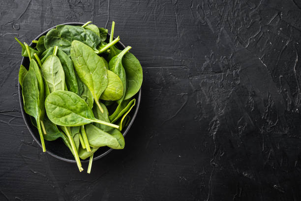istock Bundle of fresh spinach, in bowl, on black stone background, top view flat lay, with copy space for text 1326344566