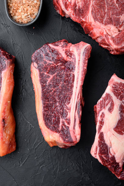 istock Thick fatty marbled raw beef club steak, on black stone background, top view flat lay 1326344731