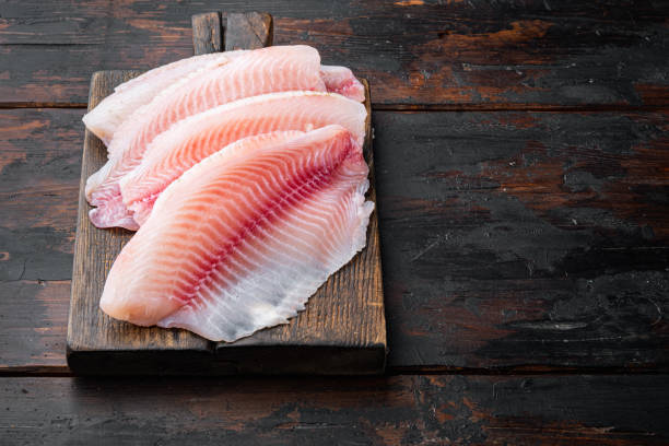 istock Tilapia fish fillet meat, on dark wooden background with copy space for text 1326345671