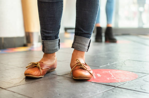 istock People standing in a line on social distancing markers 1326346596