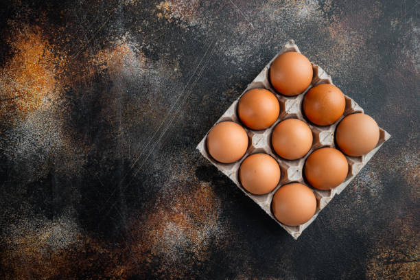 istock Chicken eggs in an egg box tray, on old dark rustic background, top view flat lay , with space for text  copyspace 1326346599