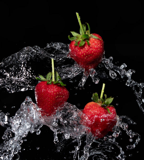 istock Fresh strawberries in the air water splash on black background 1326364829