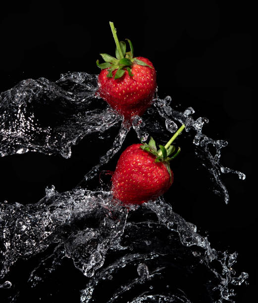 istock Fresh strawberries in the air water splash on black background 1326364867