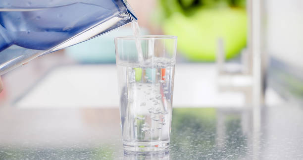 istock woman pour water into glass 1326373060
