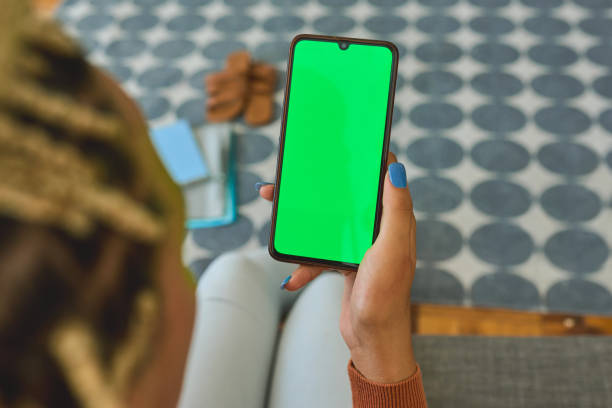 foto de un irreconocible usando un teléfono inteligente con una pantalla verde en el sofá de casa - unrecognizable person laptop holding women fotografías e imágenes de stock