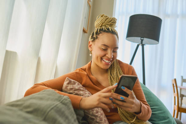 istock Shot of a young woman using a smartphone while relaxing on the sofa at home 1326374832