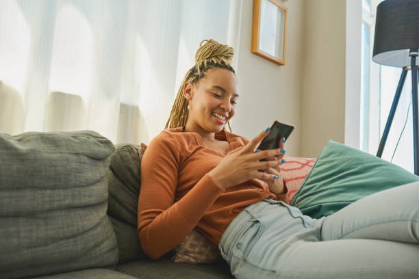 istock Shot of a young woman using a smartphone while relaxing on the sofa at home 1326374836