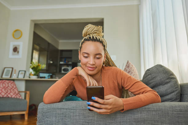 istock Shot of a young woman using a smartphone while relaxing on the sofa at home 1326374838