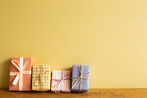 istock Colorful gift boxes on wooden table. yellow wall background 1326375879