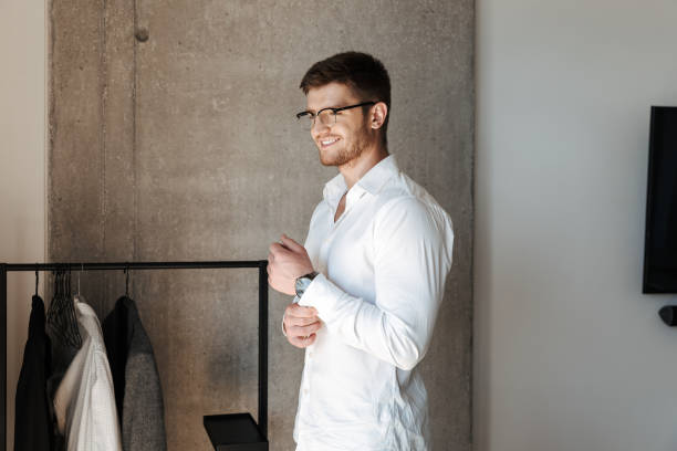 Confident young man putting on white shirt