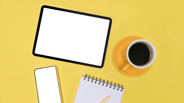 Above view digital tablet, smart phone and notebook on yellow background.