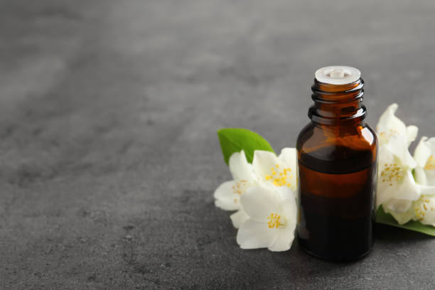 istock Essential oil and jasmine flowers on grey table. Space for text 1326392483
