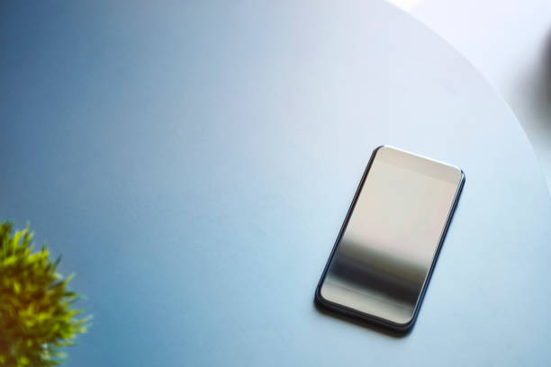 istock High angle view of smartphone on pastel light blue matt round table. 1326396158
