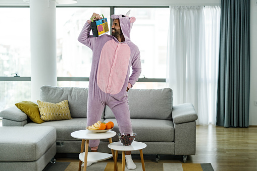 Happy man in unicorn costume enjoying while listening radio music at home.