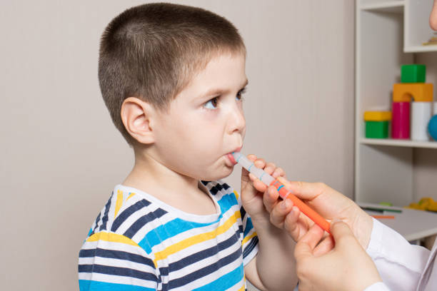 The pediatrician or nurse gives the child syrup in a measuring syringe. Treatment of cough, temperature in children. Paracetamol or ibuprofen for toddlers and preschoolers in pediatrics. child liquid medicine stock pictures, royalty-free photos & images