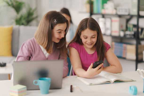 istock Girls sitting at desk and using a smartphone 1326397666