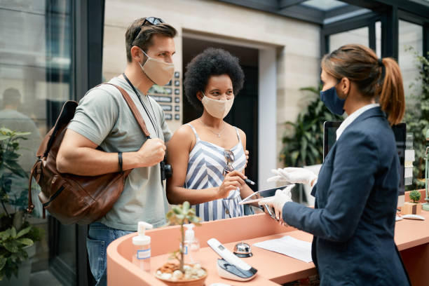 istock Happy couple signing on digital tablet while checking in a hotel during coronavirus pandemic. 1326398637