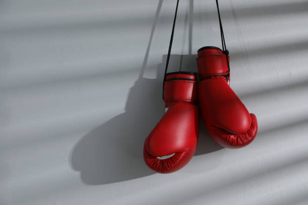 istock Pair of red boxing gloves hanging on light wall, space for text 1326399865