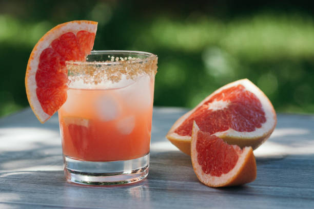 Grapefruit juice with ice in a glass on the table outdoors. stock photo