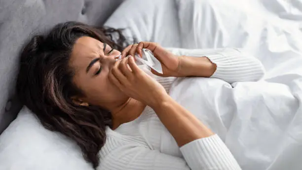 Photo of Black woman with rinny nose lying in bed