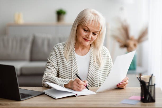 istock Smiling mature woman writing and holding document at home 1326402178