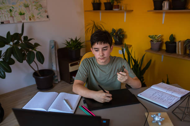 istock Boy showing the toy as a reference for what he will draw on the drawing pad for his homework 1326406378