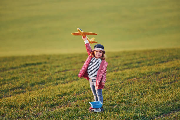 Cute little girl have fun with toy plane on the beautiful green field at sunny daytime Cute little girl have fun with toy plane on the beautiful green field at sunny daytime. beautiful multi colored tranquil scene enjoyment stock pictures, royalty-free photos & images