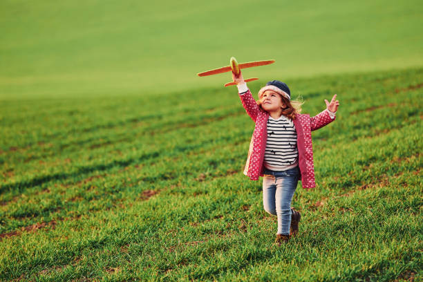 Cute little girl have fun with toy plane on the beautiful green field at sunny daytime Cute little girl have fun with toy plane on the beautiful green field at sunny daytime. beautiful multi colored tranquil scene enjoyment stock pictures, royalty-free photos & images