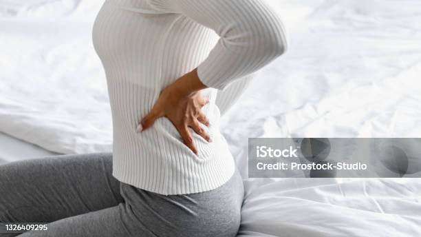 Closeup Of Black Woman With Back Pain Sitting On Bed Stock Photo - Download Image Now