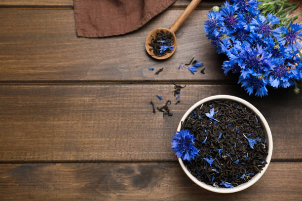 istock Composition with dry tea leaves and cornflowers on wooden table, flat lay. Space for text 1326410127