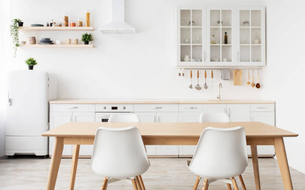 istock Scandinavian interior design. Light kitchen furniture and dining table, different utensils and kitchenware on shelves 1326410400