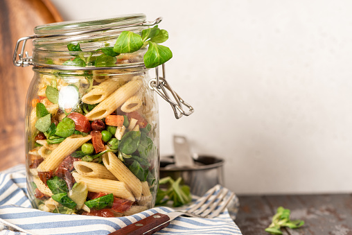 Salad with various vegetables and pasta in a jar. Vegan food, Mediterranean food. Lunch or dinner in a jar, take away