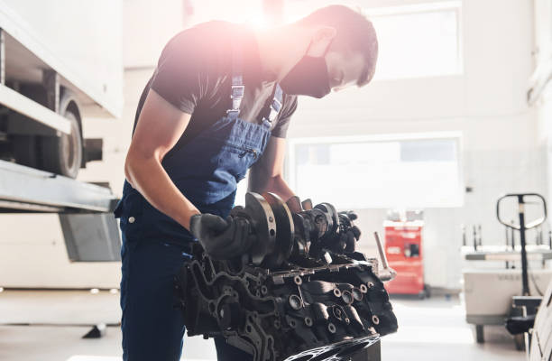 istock Beautiful lighting. Professional repairman in black protective mask works with broken automobile engine 1326411550