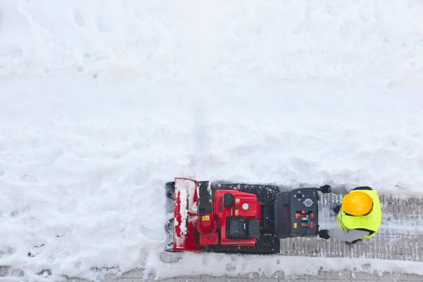 operaio che pulisce la neve sul marciapiede con un spazzaneve. inverno - snow cleaning foto e immagini stock