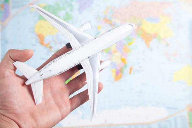 istock Male hand holding airplane on world map. Travel 1326415367