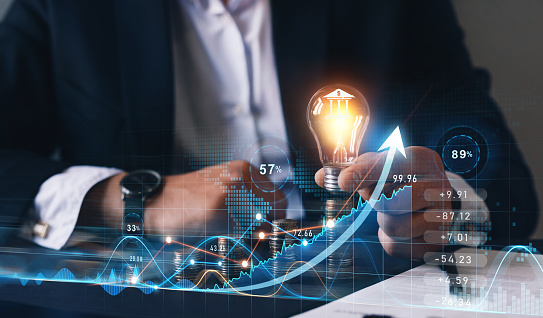 Businessman holding light bulb  with bank icon and sales data business growth graph. Financial innovation technology