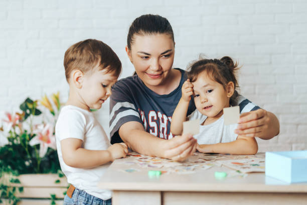 Mother playing with her children at home in cards stock photo