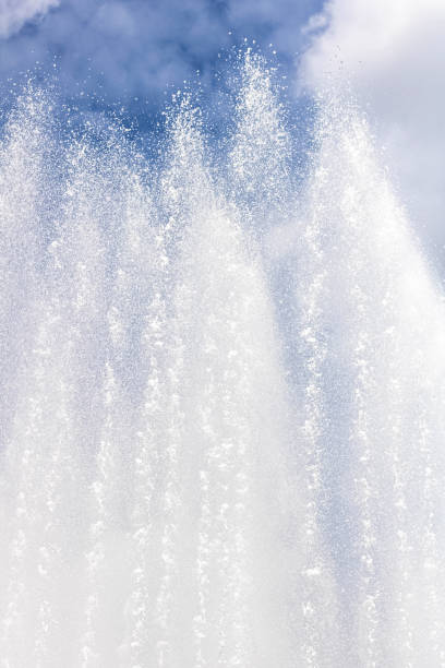 background of water jets and fountain splashes against a blue sky with clouds - well fountain water pipe pipe imagens e fotografias de stock