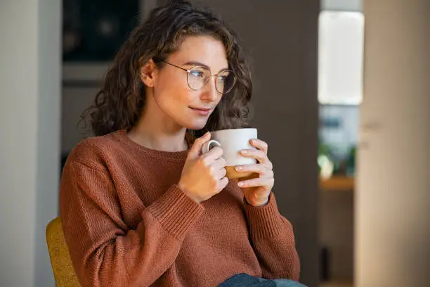 Photo of Young woman drinking tea at home during winter
