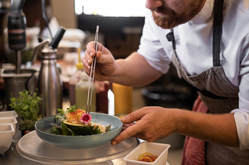 Chef placing finishing touches on a meal before serving.