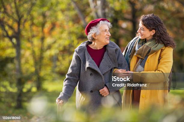 Senior Woman Walking With Granddaughter In Park During Autumn Stock Photo - Download Image Now